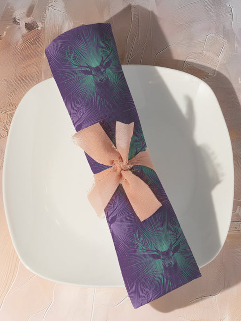 Set of four purple dining napkins featuring alternating teal and violet stag heads with radiating sunburst patterns, sized 18x18 inches.